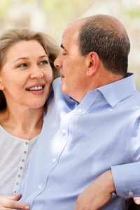 happy elderly couple hugging on a bench in  park